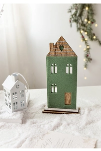 Détail d'une maison en feutre vert sur socle en bois avec éclairage de Noël chaleureux