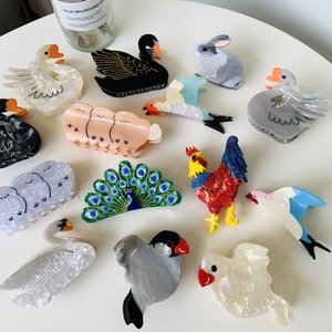 Detailed close-up of colorful acetate bird animal claw clips arranged on a white table