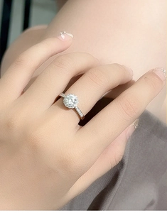 Close-up of a halo moissanite engagement ring on model finger showing brilliant sparkle