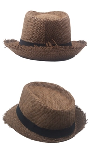 Detail of brown straw fedora hat featuring black ribbon and trendy frayed edge texture