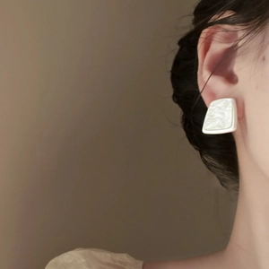 Close-up of elegant square resin earrings with pearlescent finish on a female model