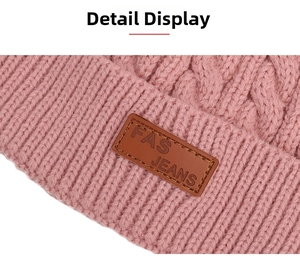 Detailed view of pink cable knit winter hat featuring premium leather brand label