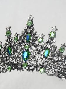 Macro view of vintage silver crown with teardrop green gemstones and emerald rhinestones