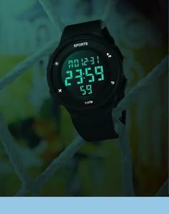 Close-up of digital sports watch with green LED backlight showing date and 5ATM waterproof