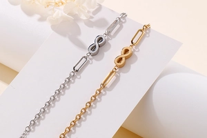 Detail of infinity symbol chain bracelets in gold and silver steel on a geometric stand