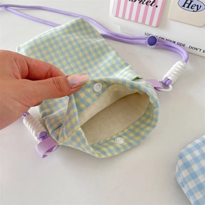 Detail shot showing the internal white snap button closure of the plaid canvas phone bag