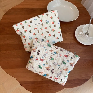 Detail of quilted cotton makeup bags with cute bear and dog prints on a wooden table
