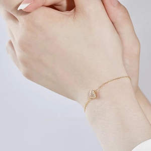 Detailed view of a gold S925 sterling silver heart bracelet with zircon on model's wrist