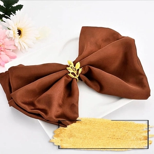 Elegant gold maple leaf napkin ring on a brown satin napkin in a white ceramic plate