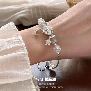 Elegant silver beaded bracelet with crystal moon and star charms on woman's wrist