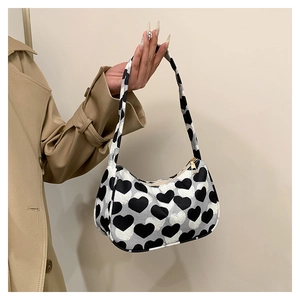 Détail d'un sac sous l'aisselle en toile à motif cœur noir et blanc avec zip doré