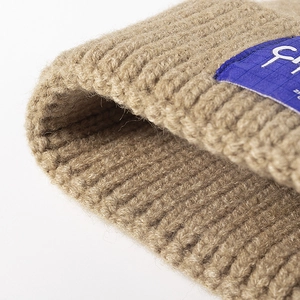 Classic camel ribbed knit beanie with blue woven label for winter warmth and fashion