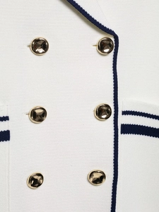 Detail van wit ribgebreid vest met gouden knopen en donkerblauwe contrastrand