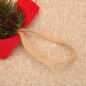 Detail of Christmas ornament featuring red burlap bow, natural pinecones and green pine needles