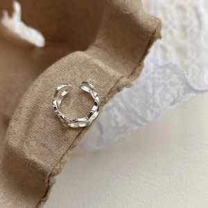 Detail shot of a silver hollow heart cuff earring with chain texture on vintage paper