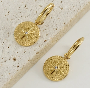 Close-up of 18K gold-plated starburst hoop earrings on natural stone background