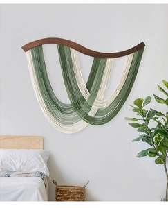 Détail de tapisserie murale boho avec poutre en bois courbée et pompons verts