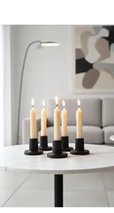 Set of five matte black glass candle holders with lit white candles on marble
