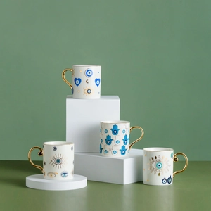 Nordic ceramic coffee mugs with gold handles and blue evil eye patterns on green background