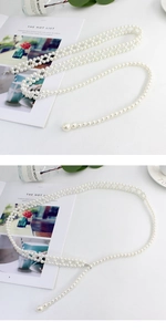Detailed macro view of elegant multi-layer white pearl waist chain with metal lobster clasp