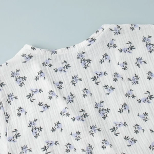 Detail of light blue floral print on white cotton crepe fabric with puff sleeve stitching