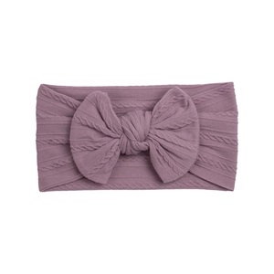 Detail of baby nylon headband with a large cable knit bow in dusty rose purple color