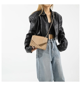 Close-up of beige quilted chain bag featuring classic V-pattern and textured stitching