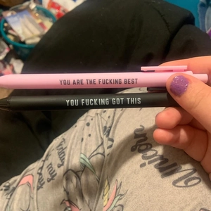 Close-up of funny pens in pink and black featuring motivational slogans for office use
