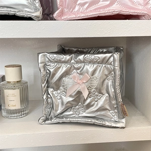 Silver quilted organizer bin with pink bow and lace detail on a white shelf