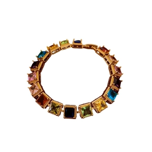 Bracelet vintage doré serti de zircons carrés multicolores sur fond blanc épuré