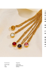 Detail of five multi-colored 18K gold birthstone necklaces on beige textured fabric