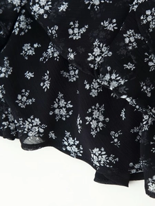 Detailaufnahme von schwarzem Chiffon-Stoff mit zarten weißen Blumenmustern für Kleider