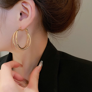 Nahaufnahme doppellagiger goldener Creolen am Modell, die das Crossover-Design betont