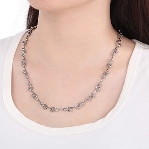 Close-up of wavy silver metal chain with small beads worn by a model on a white tee