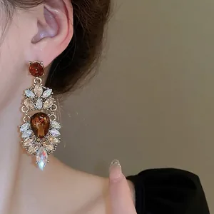 Elegant gold drop earrings with champagne crystals shown on a model side view