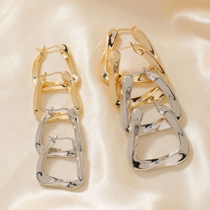 Chic U-shaped twisted metal hoop earrings in gold and silver finish on silk satin
