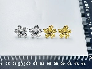 Detail view of flower-shaped stainless steel earrings in gold and silver finishes