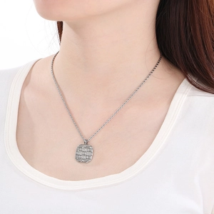 Close-up of a square pendant necklace with woven texture and crystals on a rope chain