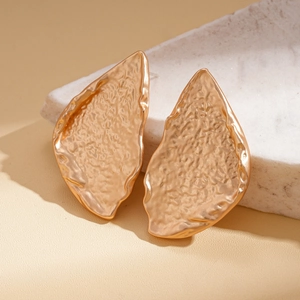 Close-up of golden hammered metal earrings with a textured wrinkled geometric design