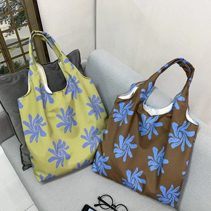 Detail of floral printed canvas tote bags with wide straps on a gray fabric sofa