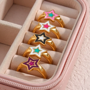 Macro detail of five colorful enamel star rings displayed in a pink jewelry box