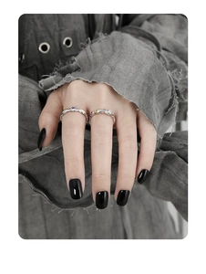 Detail of silver rings with purple and yellow zircons worn by a model in dark style
