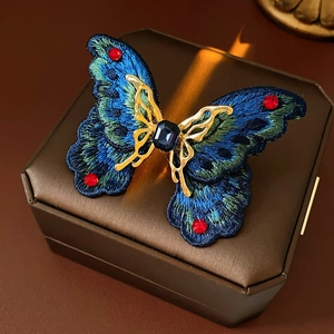 Macro detail of vintage butterfly ring featuring blue embroidery and gold metal inlay