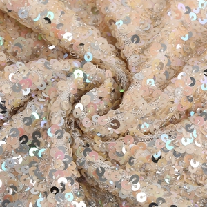 Macro shot of high-density champagne gold sequins on soft mesh for party dresses