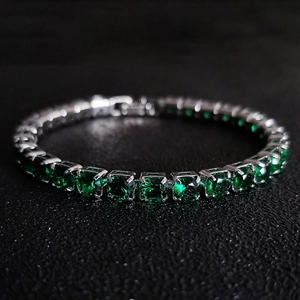Macro shot of silver tennis bracelet with square-cut deep green emerald zircon stones