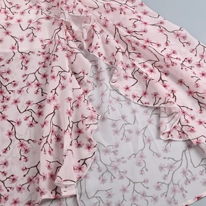 Vue détaillée du tissu en mousseline rose à fleurs avec bordure à volants délicate