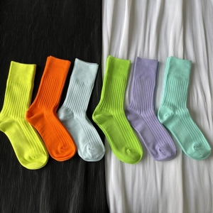 Close-up of six colorful ribbed knit crew socks neatly arranged on black and white fabric
