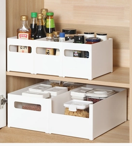 Close-up of white plastic kitchen storage boxes with handles inside a wooden cabinet