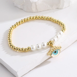 Golden bead and pearl bracelet featuring a sparkling zircon evil eye charm in gold
