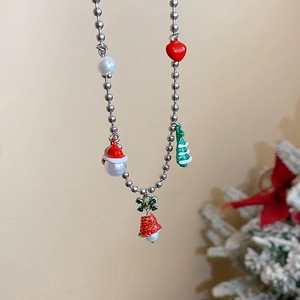 Christmas necklace with heart, tree, and bell pendants against a festive background